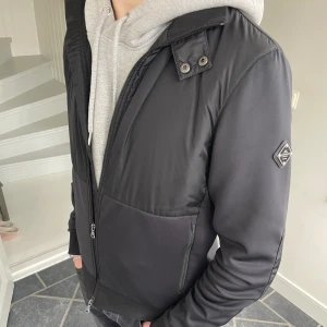 J.Lindeberg dovid hybrid jacket - J.lindeberg jacka, perfekt till våren. Jackan har lagom varm och är i skönt material. Den har inga defekter och dragkedjor funkar som de ska. Org pris 3000. Storklek S men funkar för M. Skriv om du undrar något:)