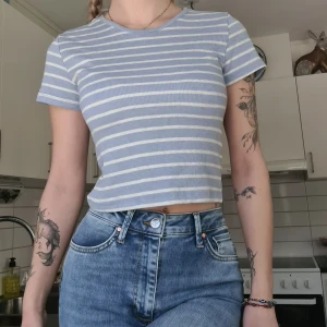 Randig t-shirt - Vit & ljusblårandig croppad t-shirt. Skönt material, storlek M men är mer som en S. Kom med prisförslag😊  Material: 62% Polyester, 33% Viskos, 5% Elastan. 