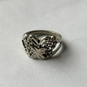 Fjäril ring vintage - En fin ring i motivet av en fjäril. Osäker på material. Den rostar ej men känns inte som stainless steel heller, kan vara järn? I fint skick iaf. Kan skicka privat med brev, frakten blir då bara 18 kr.