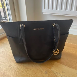 Michael Kors Väska - En Michael kors väska i svart med guld detaljer. Använd och det finns tecken på användning (bild 3-5)💗Köpt för 3500kr