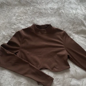 Cropped tröja - Cropped tröja med fin form under bysten. Är i storlek L men passar M. Endast använd en gång, är i mkt gott skick. Går även att använda som träningströja då materialet andas bra och täcker halva handen. 