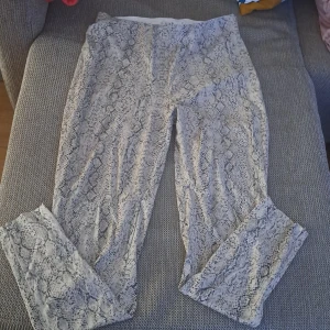 Ormmönstrade byxor - Ett par byxor med ormmönster i svart och beige. Byxorna har en dragkedja på sidan och är av normal passform. ha använt max 4 gånger. från naked och är ny. 