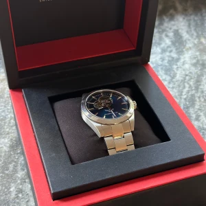 TISSOT GENTLEMAN POWERMATIC 80 OPEN HEART - Säljer en Tissot Gentleman Open Heart Powermatic 80 herruhr i mycket bra skick. Klockan är automatisk och har en blå urtavla med en synlig mekanism. Den har en stållänk och är i mycket bra skick. Klockan kommer med originalbox och papper.