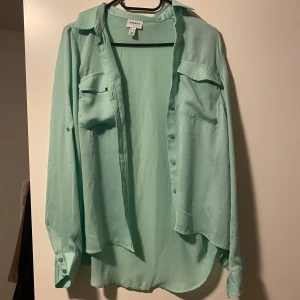 Turkos skjorta från vero Moda  - En skjorta från vero Moda. Oanvänd då jag råka köpa en för liten storlek. Den är väldigt fin och somrig. Den har två fickor på bröstet och materialet är väldigt skönt och mjukt. Köpt för 300kr säljer för 160kr ( frakt står ni själva för)