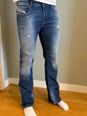 Diesel flared jeans - Säljer ett par blå jeans med raka ben och lätt slitna detaljer på låren och fickorna. Jeansen har klassisk femficksdesign och en snygg tvätt med ljusare partier framtill. Perfekta för en avslappnad och trendig look. Är 185 och sitter bra