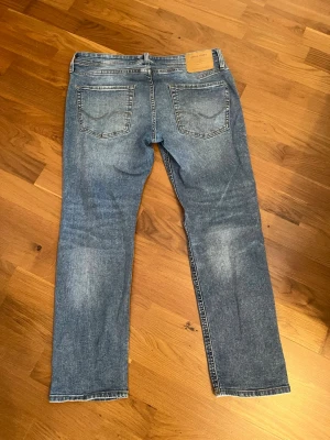 Jack and Jones jeans - Säljer ett par klassiska blå jeans med rak passform och fem fickor. Jeansen har en snygg tvättad look och normal midja. Säljer för 179kr men pris går att diskuteras. Storleken är W32 L30.