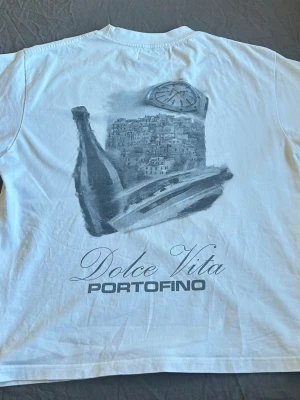 Vit t-shirt med Dolce Vita-tryck - Vit t-shirt från notresucces, personen på bilen är ca 180cm men som är lite liten men passar dig som är något kortare och perfekt för dig som gillar stilrena och unika motiv.