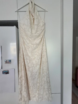 Vit halterneckklänning med blommönster - Säljer en krämvit halterneckklänning med subtilt blommönster från Gina Tricot. Strl XL men passar mig som normalt har strl M.