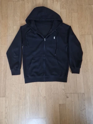Marinblå Polo Ralph Lauren zip hoodie  - Marinblå Polo Ralph Lauren zip hoodie i mycket fint skick. Sparsamt använd och utan hål eller fläckar. Broderad Polo-logga på bröstet, dragkedja och huva med dragsnören. Bekväm och stilren hoodie som passar till det mesta.  Storlek: (S)  Pris: 750 kr (kan diskuteras vid snabb affär).