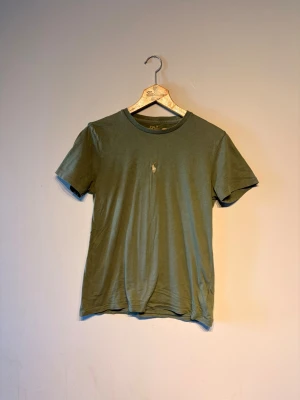 Olivgrön t-shirt från Polo Ralph Lauren - Snygg olivgrön t-shirt från Polo Ralph Lauren med klassisk rund hals och korta ärmar. På bröstet finns den ikoniska broderade loggan i vitt. Tillverkad i mjuk bomull som känns skön mot huden. Perfekt till jeans eller shorts.