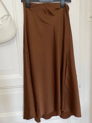 Rare skimrig Satin kjol - Rare brun färg på midi/maxi satin kjol. Använd 2 ggr. En gång i rikstan en gång för provning.  Org pris: ca 3-4 hundra. Köpt i en fin butik i Karpathos stad.