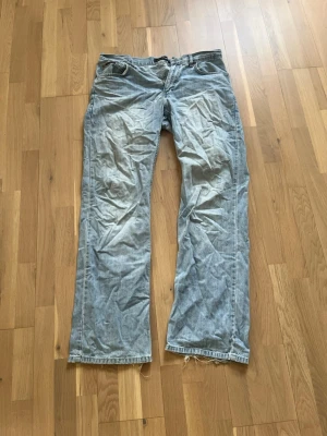 Ljusblå jeans från Blend - Säljer ett par ljusblå jeans från Blend med raka ben och klassisk femficksmodell. Jeansen har råa kanter nedtill och är tillverkade i denim. Perfekta för en avslappnad och trendig look.