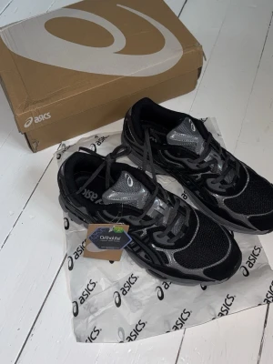 Asics Gel Nyc Graphite sneakers - Snygga Asics Gel Nyc skor i färgen Grahpite med Ortholite-innersula för extra komfort. Skorna har mesh- och syntetdetaljer, klassisk snörning och låg profil. Perfekta för dig som gillar sportig stil och vill ha något bekvämt till vardags. Storlek 45 men kan nog bäras av mindre storlekar då dom är lite små i modellen