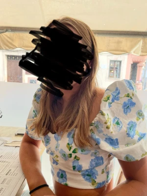 Blommig blus med puffärm - Söt blus med blåa och gröna blommor på vit botten. Toppen har puffiga korta ärmar. Perfekt för sommarens alla tillfällen och ger en fräsch och trendig look. Använd en sommar! 