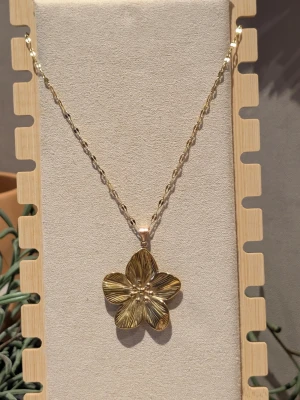 Halsband med blomma - Halsband med hänge i guldfärgat rostfritt stål. Kedjan är 40 + 5 cm. Vacker och användbart då det passar till allt.