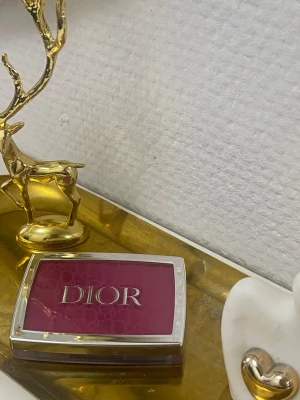 Dior Rosy Glow 006 Berry Rouge - Dior Rosy Glow i nyansen 006 Berry är ett puderrouge som ger en naturlig glow. Kommer i en elegant, genomskinlig ask med silverdetaljer och tydlig Dior-logga. Färgen är en djup bärig rosa som passar perfekt för att fräscha upp kinderna.