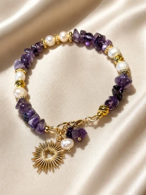 Armband med ametister och sötvattenspärlor - Armband med ametister och sötvattenspärlor. Mellandelar av guldfärgad rostfritt stål. Hängen med pärlor och en sol i rostfritt stål. Armbandet är ca 18 cm. Går att förlängas om man önskar längre. Handgjort av mig. Endast ett exemplar.