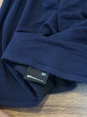 Mörkblå kjol från Gina Tricot XXS - En enkel och stilren mörkblå kjol från Gina Tricot i mjukt material. Kjolen har en rak passform och är perfekt för dig som gillar minimalistisk stil. Passar till många olika looks och är lätt att matcha med andra plagg. Den har en defekt på andra bilden där jag skulle torka den med en hårfön men råkade bränna den annars är kjolen super tajt och fin. Original priset runt 300kr tror jag 