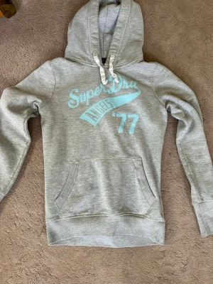 Superdry hoodie🩵 - Säljer denna super snygga superdry hoodien med ljusblått tryck där fram och även tjocka band till luvan. Den är i storlek S men jag skulle säga att den passar mer som en XS🥰 den har inga defekter. Skriv till mig vid fler frågor!