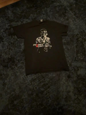 Svart t-shirt med tryck Quincy Promes - Cool svart t-shirt med ett stort tryck av Quincy Promes på framsidan. T-shirten har korta ärmar och rund hals. Perfekt för dig som gillar unika motiv och sportinspirerad stil.