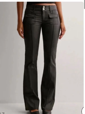 Svarta bootcut skinnbyxor - Säljer ett par svarta bootcut skinnbyxor som är lågmidjade från Nelly. Sparsamt använda. 