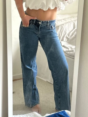 Low waist jeans  - Säljer ett par klassiska blå jeans med rak passform och låg midja. Jeansen har bälteshällor och stängs med knapp och dragkedja. Perfekta till en avslappnad och trendig look. 