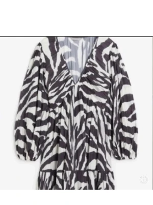 Zebramönstrad h&m klänning - Snygg kort klänning med zebramönster i svart och vitt. Klänningen har v-ringning, långa puffärmar och ett luftigt fall. Perfekt för dig som vill sticka ut med ett djurmönster och en trendig look.