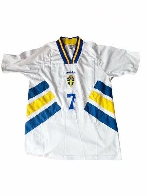 Sverige VM-tröja 1994 – Larsson #7 - Klassisk Sverige bortatröja från VM 1994 med Larsson #7 på ryggen. Adidas original i storlek M. Mycket fint skick – perfekt för samlare och fotbollsfans. Kan säljas billigare emot direkt swish.