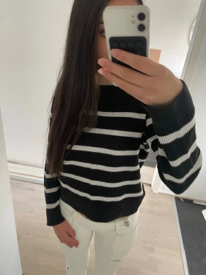 Svartvitrandig stickad tröja - Säljer en svart stickad tröja med vita horisontella ränder. Tröjan har rund halsringning, långa ärmar och en avslappnad passform. Perfekt för dig som gillar en enkel men snygg stil. Materialet känns mjukt och bekvämt mot huden. Storleken är 150 men passar perfekt till nån som 170