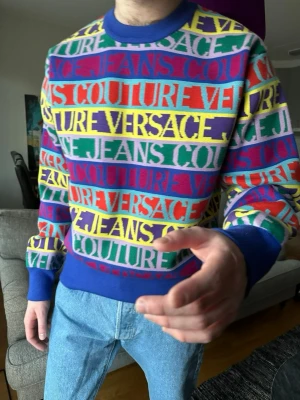 Versace sweatshirt - Färgglad tröja från Versace Jeans Couture med logotypmönster i blått, rött, gult, grönt, lila och vitt. Tröjan har blå ribbade muddar och nederkant. Perfekt statement-plagg för dig som gillar att sticka ut. Nypris ca 4500 kr, storlek M💫