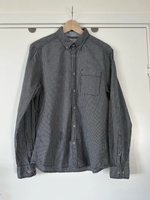 ESPRIT svart grå rutig skjorta med uppvikbara ärmar - storlek M - Stilren svart vit grå rutig långärmad skjorta från ESPRIT i storlek M. Tidlös modell med knappar framtill och en bröstficka. Ärmarna kan fästas upprullade med en knapp och rem. Skjortan har en klassisk krage med knappar. 100% bomull, så bra material som andas. Tidlös klassiker som passar till allt. Nypris 900:-. Mycket gott skick, som ny!