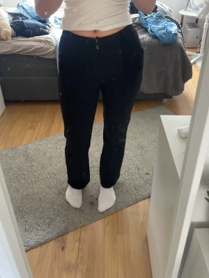 Svarta raka kostymbyxor - Snygga svarta kostymbyxor med rak passform och hög midja. Byxorna har klassisk design med hällor för skärp och dragkedja fram. Perfekta för en stilren look och passar till många olika outfits.