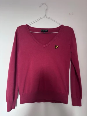 Lyle & Scott tröja  - Snygg rosa tröja från Lyle & Scott med V-ringning och klassisk gul logga på bröstet. 