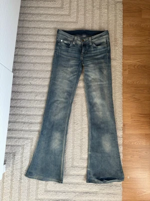 Blå bootcut jeans från Cheap Monday - Säljer ett par blå bootcut jeans från Cheap Monday med slitna detaljer och klassisk femficksmodell. Jeansen har en ljus tvätt och vida ben som ger en retrovibe. Helt nya och aldrig använts pga för små 