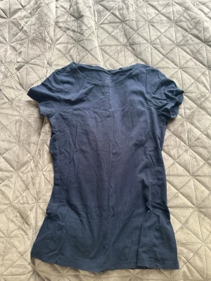 Mörkblå basic t-shirt från Kappahl - En enkel och stilren mörkblå t-shirt från Kappahl, Our Best Basics. Tillverkad i mjuk ekologisk bomull med rund hals och korta ärmar. Perfekt till jeans eller shorts för en clean look.