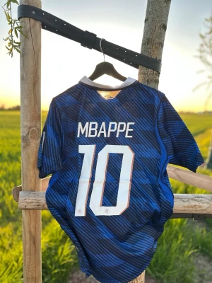 Frankrike Mbappé matchtröja VM 2026 - strl M - Helt ny och oanvänd snygg blå matchtröja med Frankrikes landslagslogga och nummer 10 Mbappé på ryggen. Tröjan har krage, korta ärmar och är tillverkad i ett lätt och ventilerande material. Storlek M. Snygg fit och bra skick. DM för eventuella frågor eller bilder.