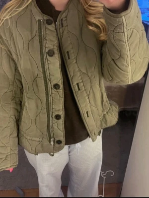 Olivgrön quiltad jacka från Zara - Quiltad olivgrön jacka från Zara i storlek S. Både dragkedja och knappar framtill. Har en liten skiftning på armen men man ser det knappt. 