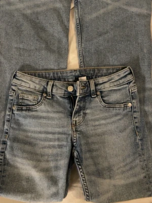 Ljusblåa bootcut jeans - Säljer ett par superfina low waist bootcut-jeans från H&M. Använda endast 2 gånger så de är i jättefint skick. Jeansen har en snygg ljus denimtvätt. Dom är bootcut längst ner för en väldigt fin passform. Jag är 167 cm lång och de sitter perfekt i längden på mig. Väldigt sköna och enkla att matcha till allt.