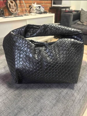 Svart flätad handväska i konstläder - Trendig svart handväska med flätad struktur och mjuk, boxig form. Väskan har ett kort handtag och är tillverkad i konstläder som ger en lyxig känsla. Perfekt accessoar för att lyfta din outfit med en modern touch.