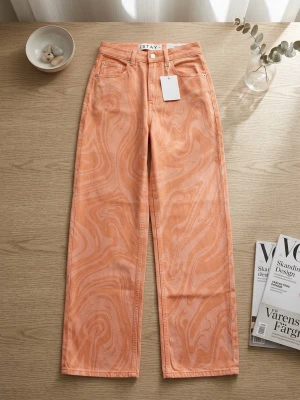 Orange swirlmönstrade jeans från ISTAY - Säljer ett par unika orange jeans från ISTAY med swirlmönster och raka ben. Jeansen har klassisk femficksdesign, hällor för bälte och knappgylf. Perfekta för dig som vill sticka ut med färg och mönster. Materialet är denim i bomull.
