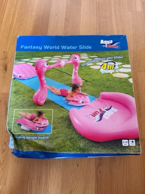 Aqua Fun Fantasy World vattenslide - Rolig vattenslide för trädgården från Aqua Fun, Fantasy World Water Slide. Den är 4 meter lång och har rosa uppblåsbara figurer och en boogie board. Perfekt för sommardagar och vattenlek utomhus. Passar barn mellan 5-10 år.