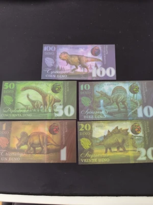 Färgglada dinosauriesedlar leksakspengar - Säljer ett set med färgglada leksakspengar med dinosauriemotiv. Sedlarna har olika valörer och visar bland annat Tyrannosaurus, Triceratops, Stegosaurus och Diplodocus. Perfekt för lek eller samling! Materialet är papper och varje sedel har unika illustrationer.