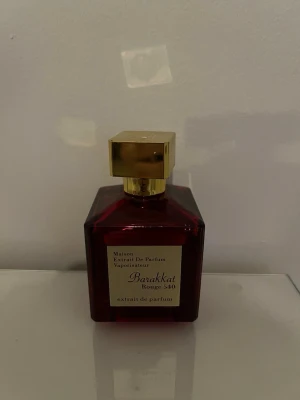 Barakkat Rouge 540 parfym - Lyxig parfymflaska från Barakkat i modellen Rouge 540. Flaskan är fyrkantig och djupt röd med en elegant guldig fyrkantig kork. Märkets etikett sitter framtill i guld och svart. Perfekt för dig som gillar exklusiva dofter och snygg design. Endast sprayad en gång.