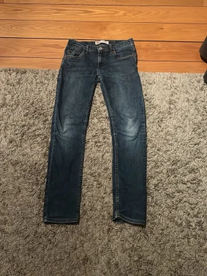 Levi's 512 slim taper - Säljer ett par klassiska mörkblå jeans från Levi's med raka ben och femficksmodell. Jeansen har snygga slitningar framtill och kontrastsömmar. Tillverkade i slitstark denim som passar perfekt till en avslappnad stil. 152 cm