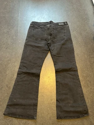 Svarta bootcut jeans - Säljer ett par svarta bootcut jeans med klassisk femficksdesign och utsvängda ben. Jeansen har en mörk tvätt och är tillverkade i ett mjukt denimtyg. Perfekta för dig som gillar retrovibbar och vill ha en snygg siluett.