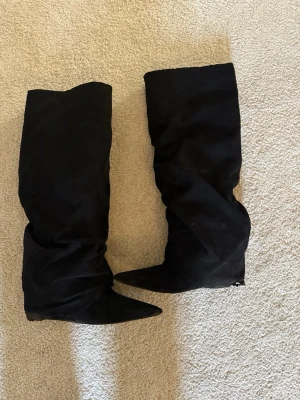 Svarta slouchy stövlar med spetsig tå - Säljer ett par svarta stövlar från Nelly med slouchy skaft och spetsig tå. Stövlarna har dragkedja på insidan och är tillverkade i mockaimitation. Använda typ 3 gånger men kan behöva tvätta då dem är använda under vinter halvåret, slitna på ena skorna nere vid hälen min inte så syns när man har på dem!☺️❤️
