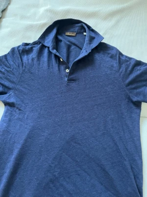 Marinblå pikétröja från Stenströms - Klassisk marinblå pikétröja från Stenströms med korta ärmar och två knappar vid kragen. Tillverkad i mjuk bomull som känns skön mot huden. Perfekt för en avslappnad men ändå stilren look.