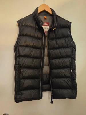Parajumper väst - Säljer en parajumper väst som passar perfekt till våren väldigt bra skick och inga hål. Storlek är Y-L sitter som M med en perfekt passform som är stilren och glansig. Hör av dig vid funderingar!