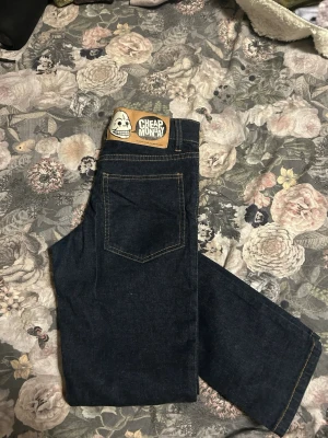 Mörkblå Cheap Monday jeans - Säljer ett par mörkblå jeans från Cheap Monday med klassisk femficksmodell och raka ben. Jeansen har kontrastsömmar och en ikonisk logga med dödskalle på bakfickan. Perfekta för dig som gillar en enkel och stilren look.