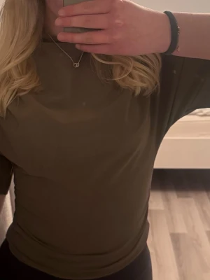 Brun topp med halvpolo - Säljer en brun topp med halvpolo och halvlånga ärmar. Toppen har en loose passform och är tillverkad i mjukt, stretchigt material som känns skönt mot huden. Perfekt att styla med jeans eller kjol för en clean look.